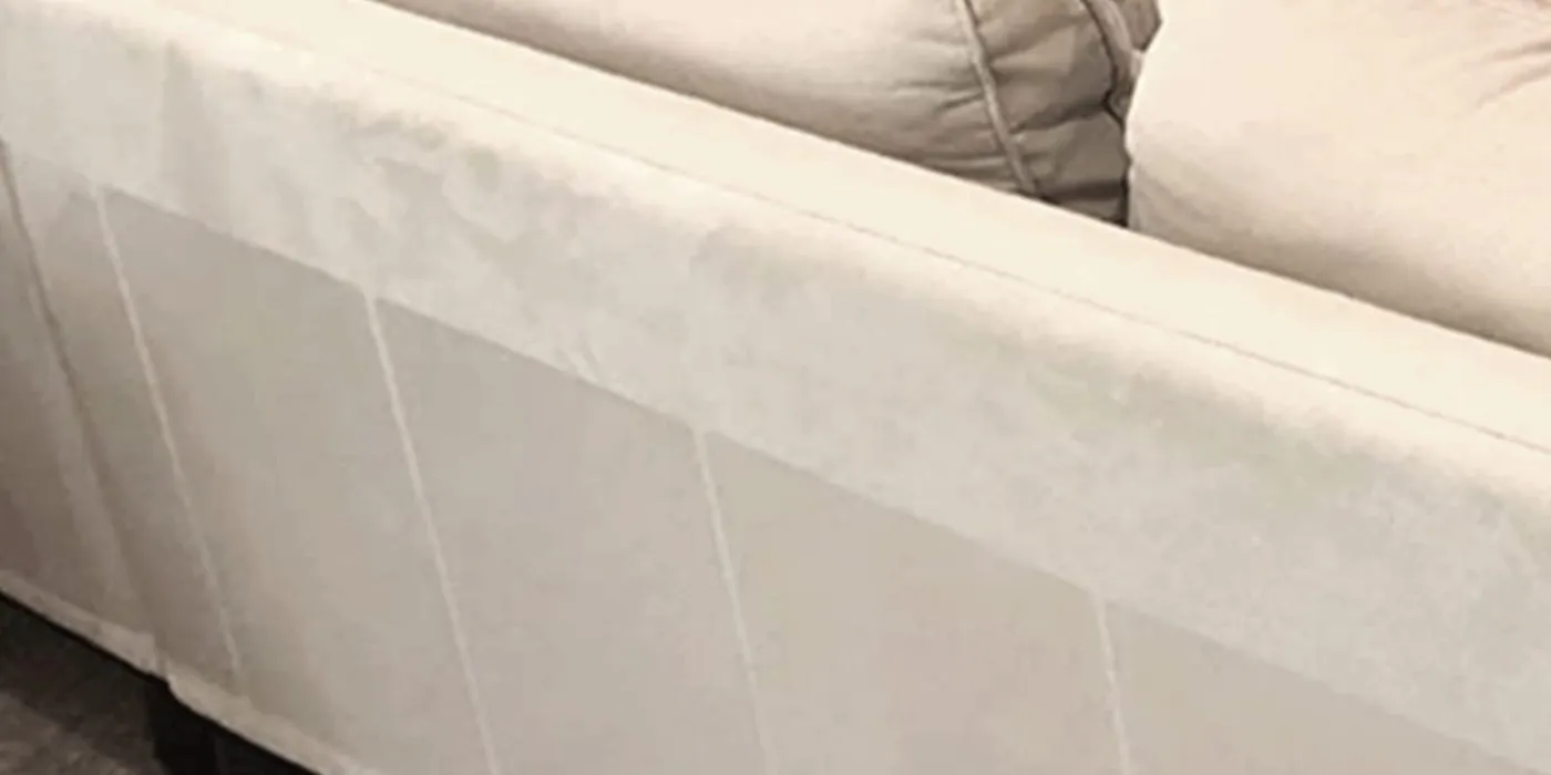 Clear furniture protector sheets applied along the side of a cream upholstered sofa